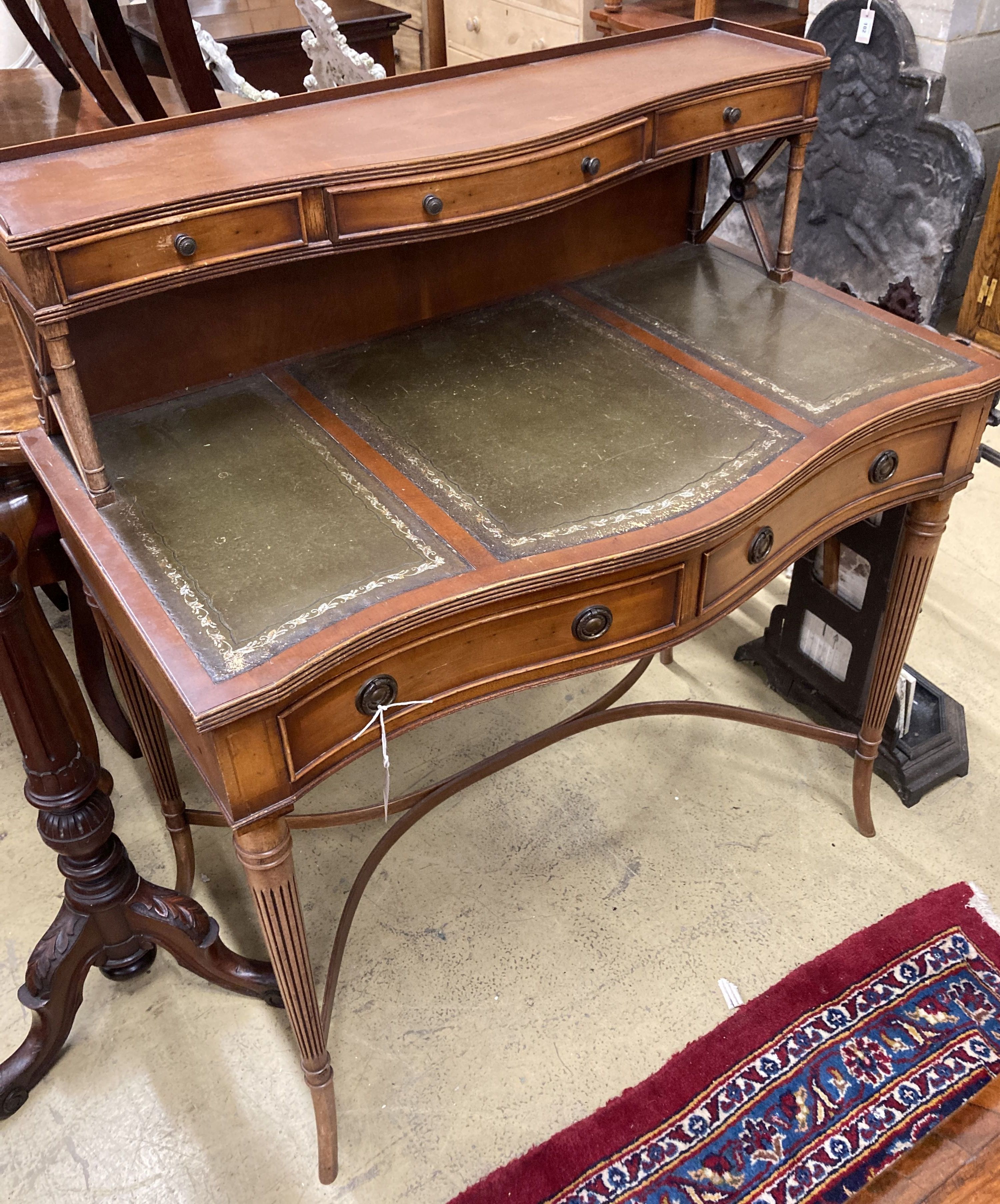 A reproduction yew serpentine writing table, width 92cm, depth 50cm, height 103cm